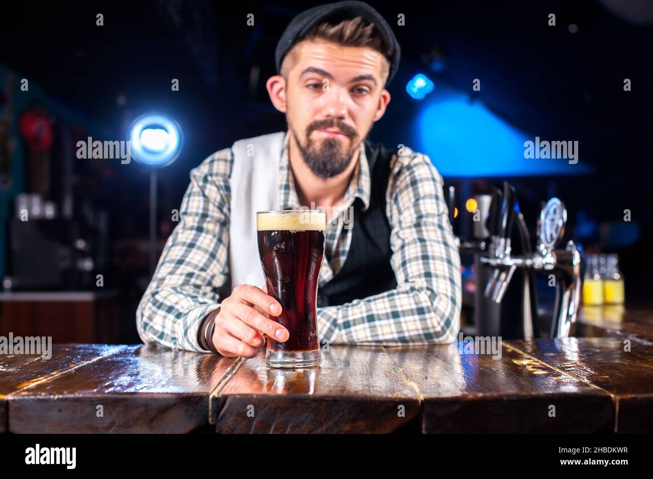 Charming bartending is pouring a drink while standing near the bar