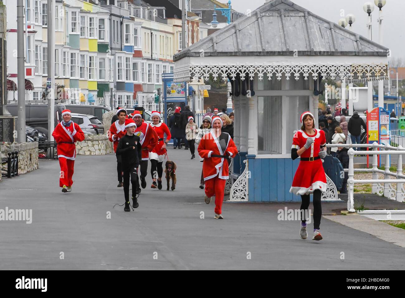 Weymouth, Dorset, UK.  19th December 2021.  Hundreds of runners dressed as Santa take part in the annual the Chase The Pudding pre-chistmas run on Weymouth beach in Dorset.  The annual event is raising money for the charity Will Mackaness trust.  Runner on The Esplanade heading for the finish line.  Picture Credit: Graham Hunt/Alamy Live News Stock Photo