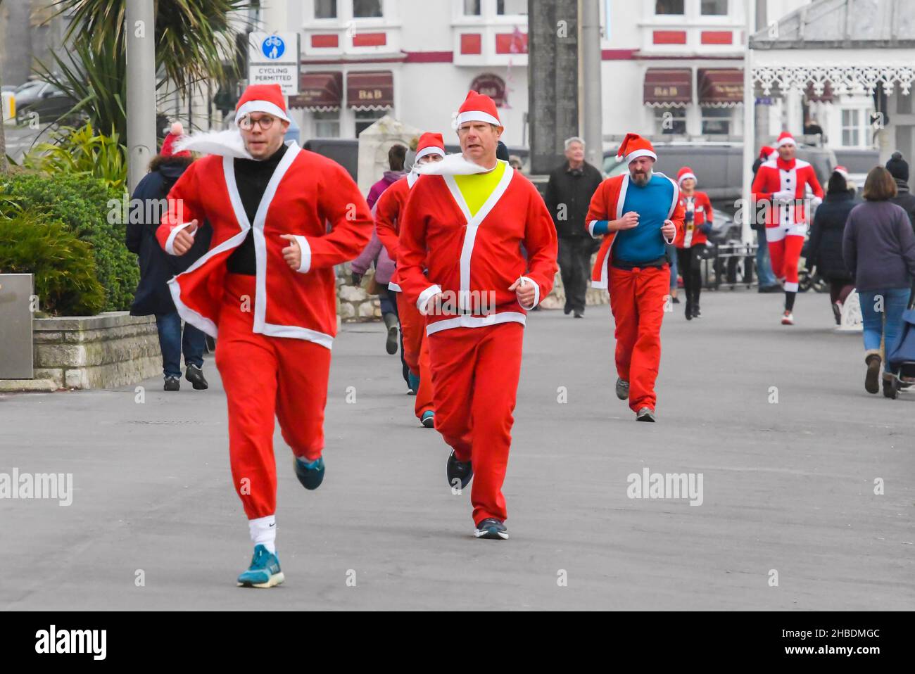 Weymouth, Dorset, UK.  19th December 2021.  Hundreds of runners dressed as Santa take part in the annual the Chase The Pudding pre-chistmas run on Weymouth beach in Dorset.  The annual event is raising money for the charity Will Mackaness trust.  Runner on The Esplanade heading for the finish line.  Picture Credit: Graham Hunt/Alamy Live News Stock Photo