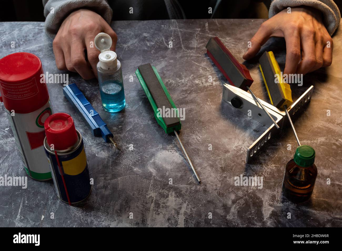 Hands of a knife sharpener. Tools for sharpening knives and scissors
