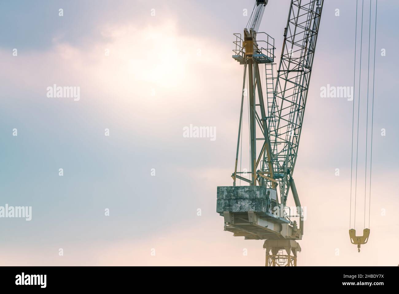 Construction crane against blue and pink sky. Real estate industry. Construction crane use reel lift up equipment in construction site. Crane for rent Stock Photo