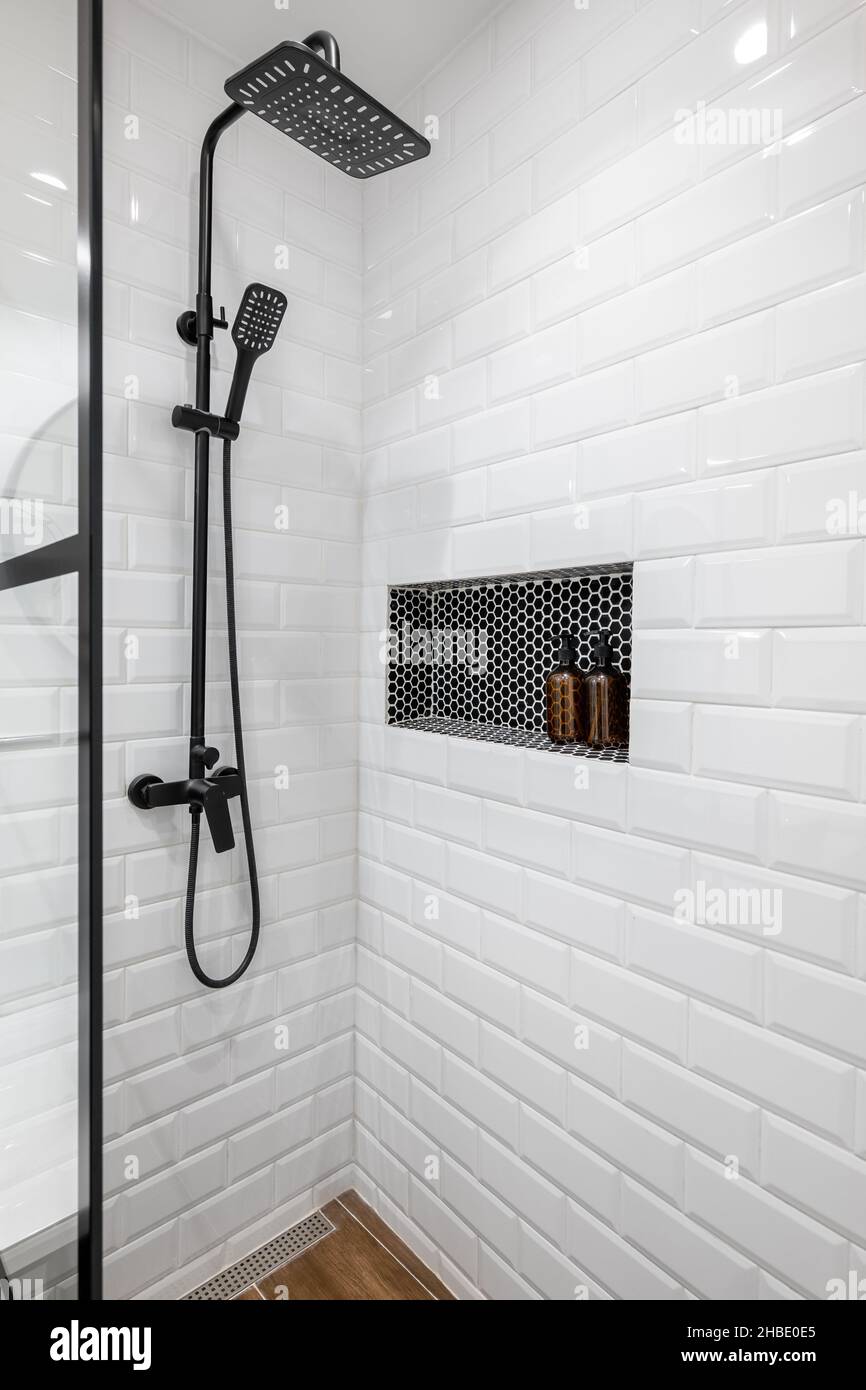 https://c8.alamy.com/comp/2HBE0E5/new-black-shower-head-on-holder-in-white-tiled-bathroom-in-modern-apartment-2HBE0E5.jpg