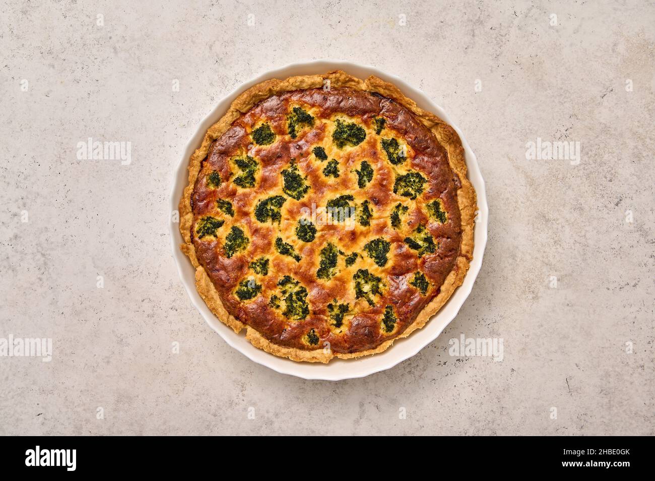 Quiche pie with broccoli, tuna and cheese in white baking dish. Flat