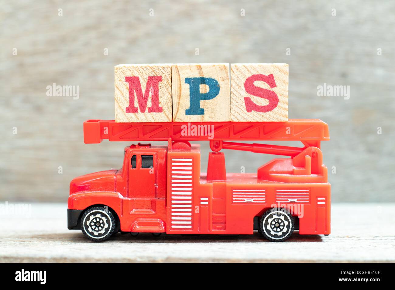 Fire ladder truck hold letter block in word MPS (Abbreviation of Master Production Schedule or Mucopolysaccharidosis) on wood background Stock Photo