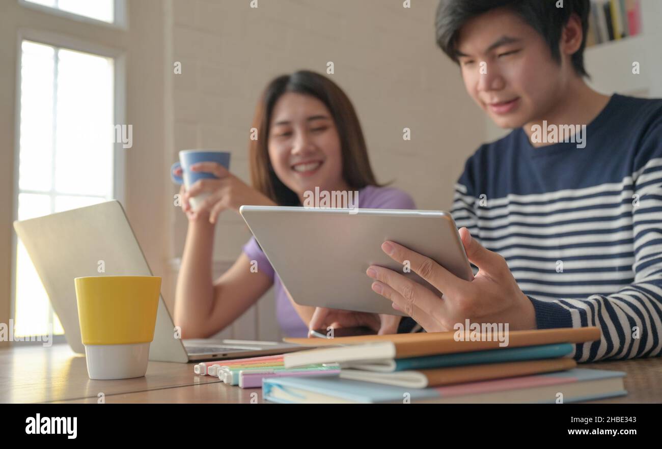 Young men and young women were taking a video conference on their tablets, They were reading exam preparation books. Stock Photo