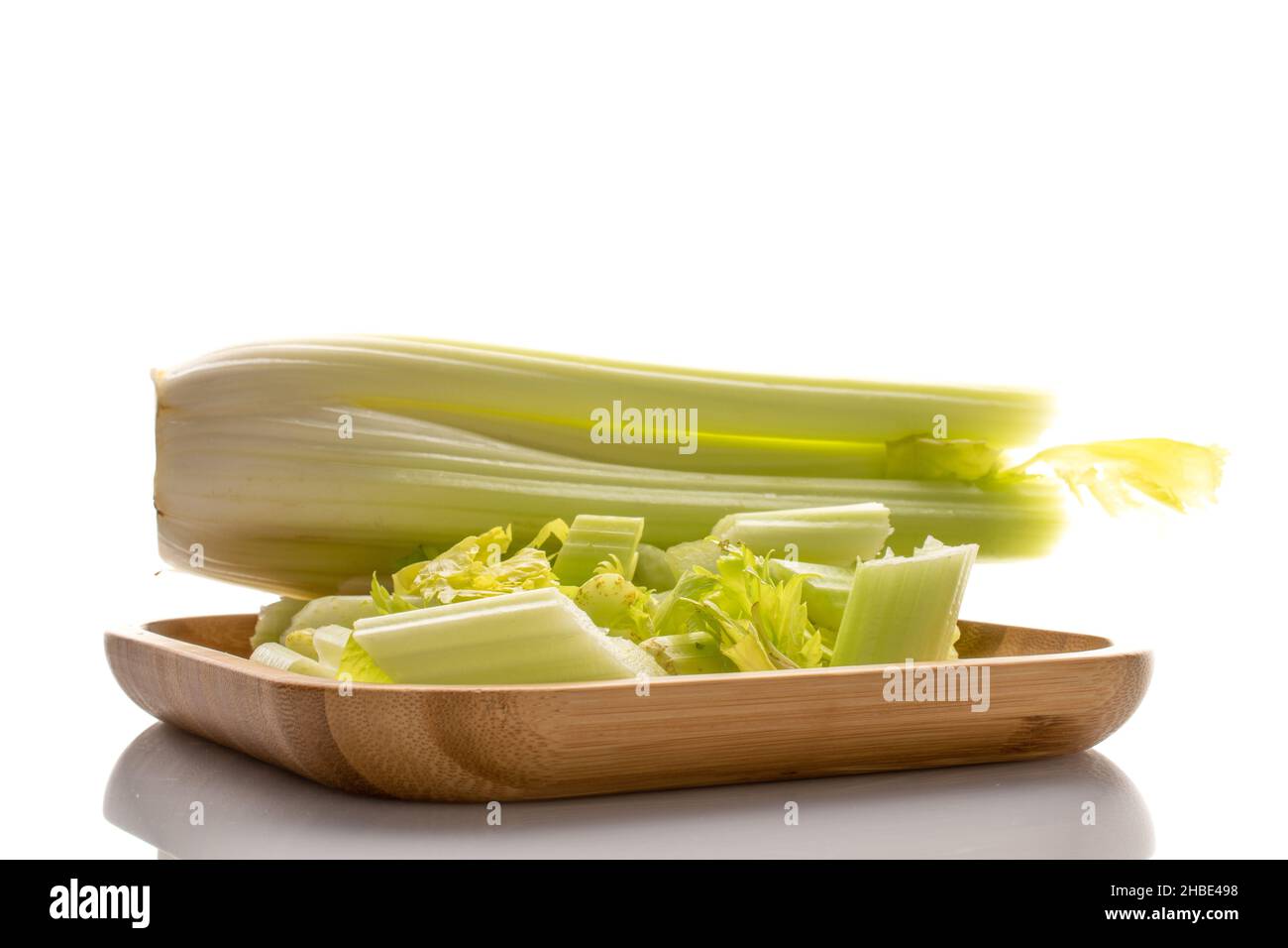 Green ripe organic celery stalks on a bamboo plate, close-up, isolated on white. Stock Photo