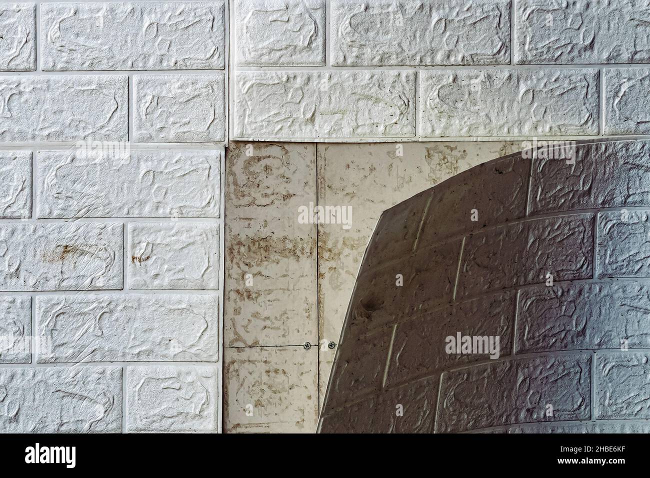 The wallpaper begins to peel off. Old white bricks wallpaper peeled off from the wall inside the