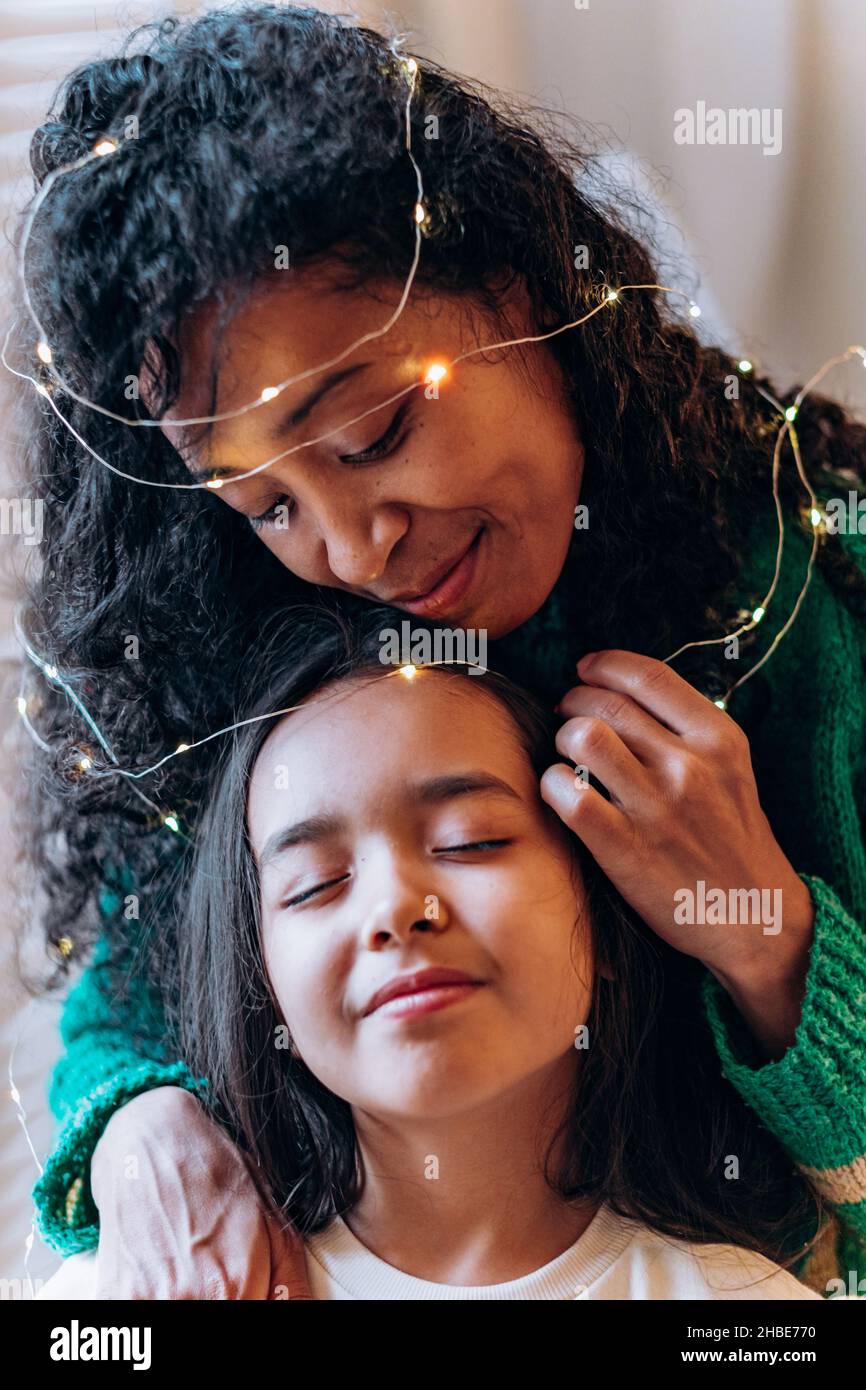 girl and long curly haired African American mother pose with