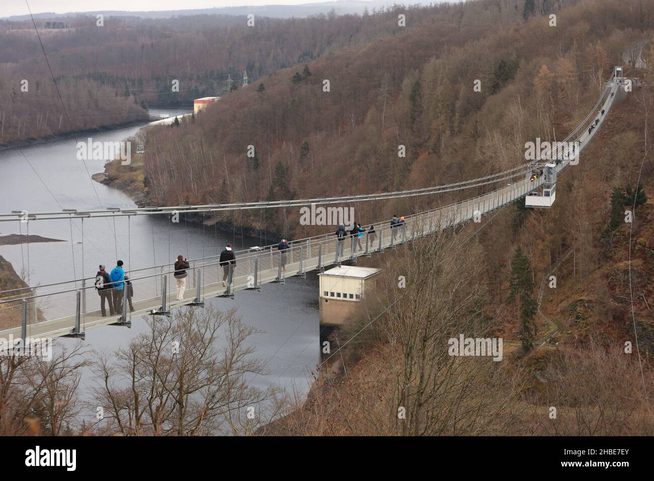 19 December 2021, Saxony-Anhalt, Hasselfelde: Visitors and tourists walk over the suspension bridge at the Rappbode dam. With the beginning of the early holidays in Saxony-Anhalt, many guests were attracted to the Harz Mountains with its tourist attractions. Photo: Matthias Bein/dpa-Zentralbild/dpa Stock Photo