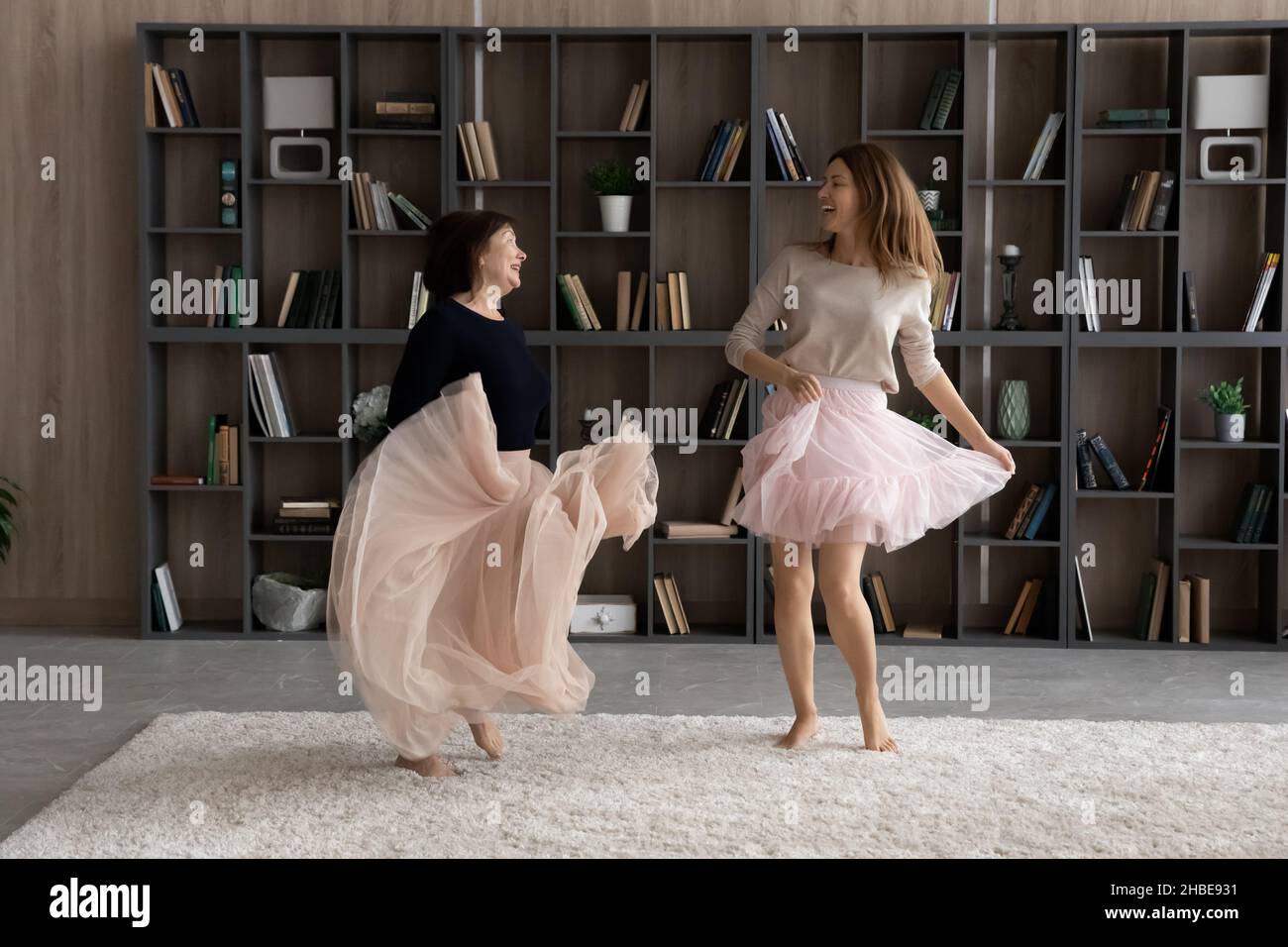 Joyful adult daughter and mother pensioner dancing in fluffy skirts Stock Photo