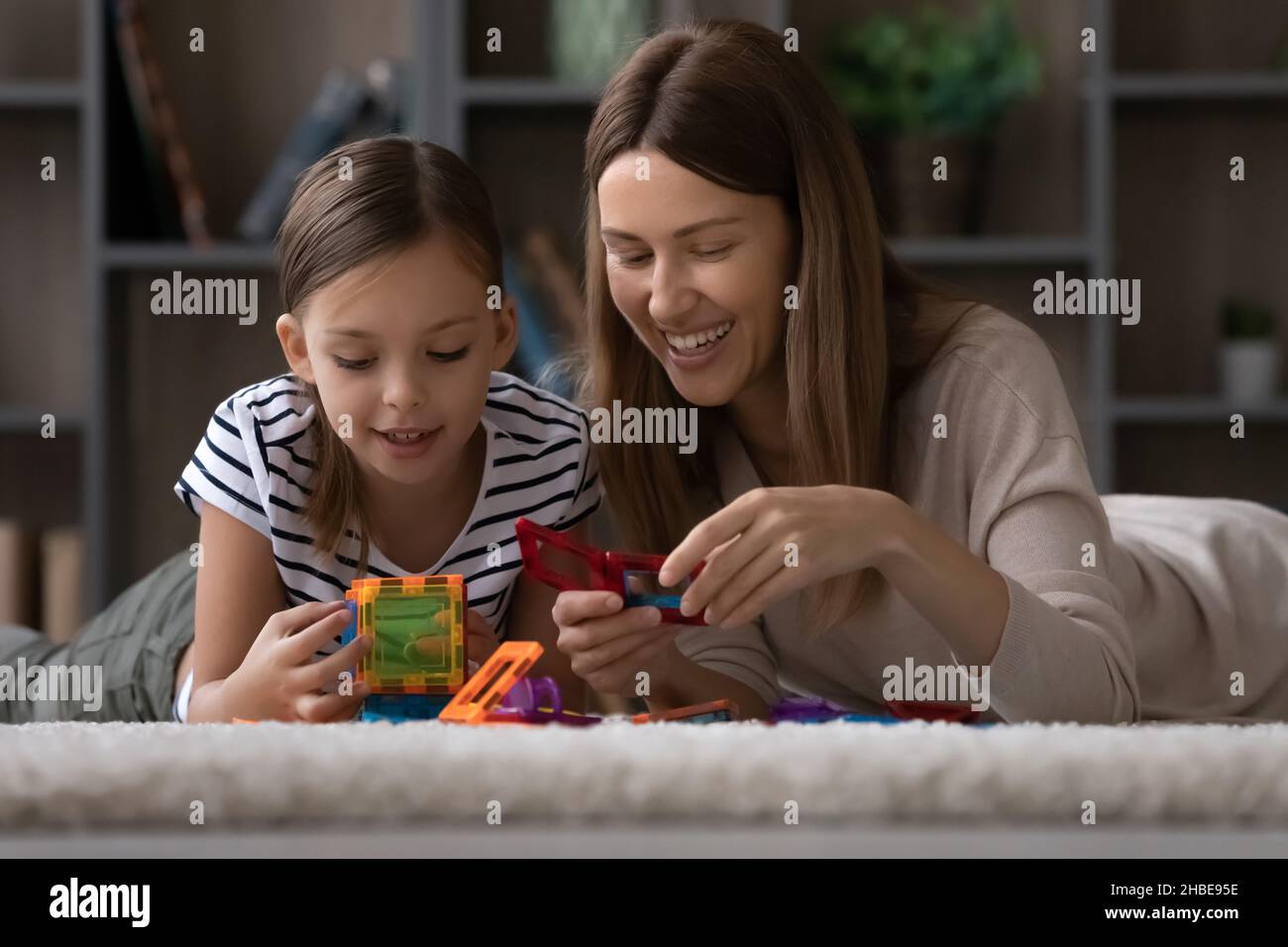 Young female babysitter and child girl play with constructor set Stock Photo