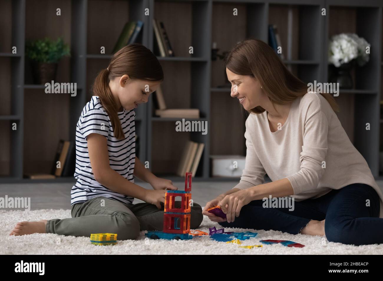 Grown elder and younger sisters engaged in building from constructor Stock Photo