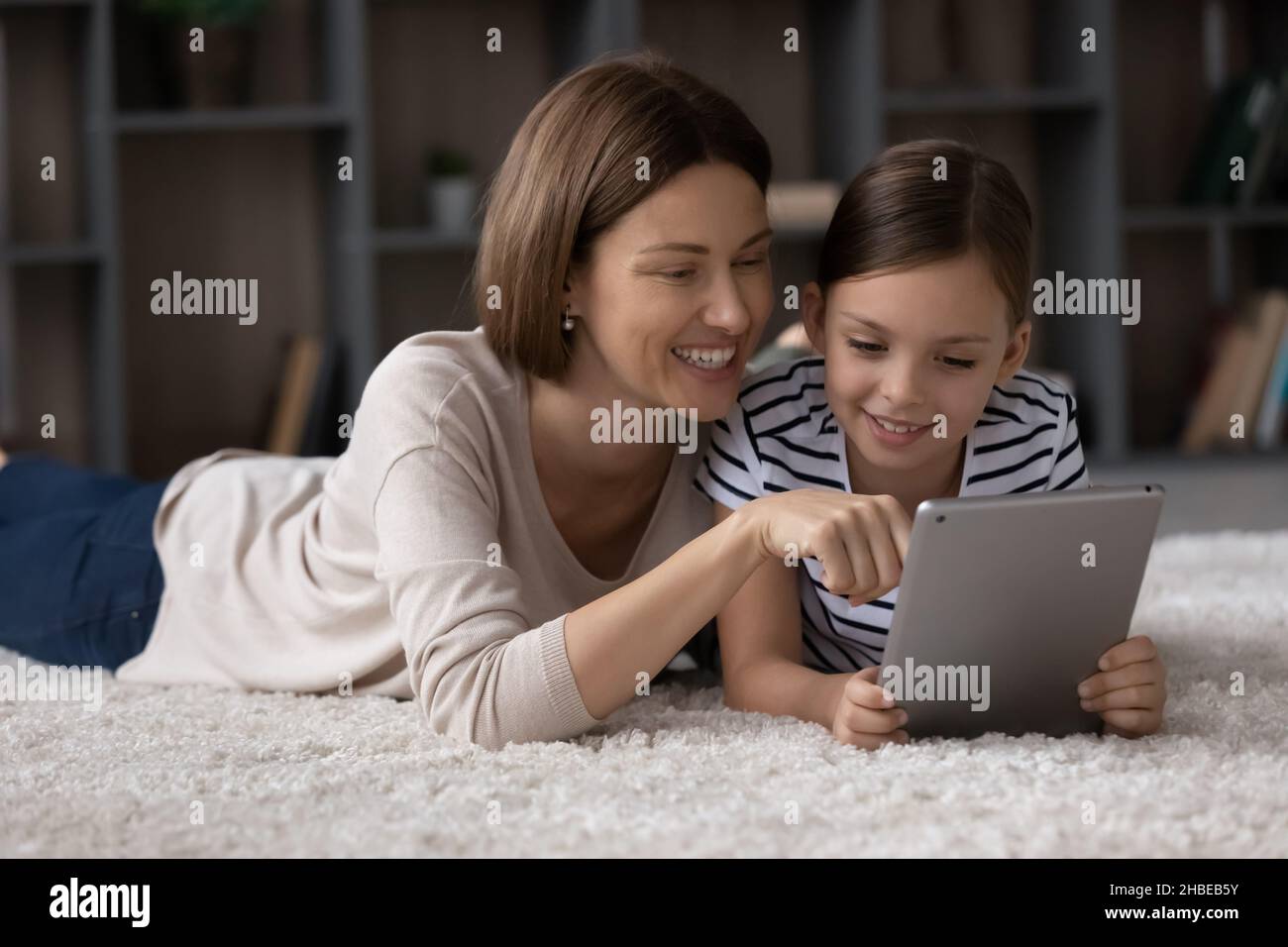 Smiling single mom show photo on tablet to preteen daughter Stock Photo