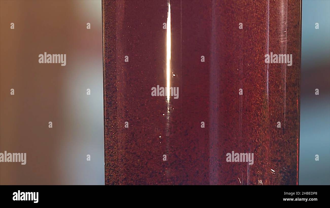 Gas bubbles float in a plastic bottle with dark blue liquid. Red liquid