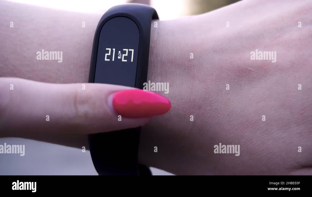 The girls wore a fitness bracelet. Girl checks pulse on fitness