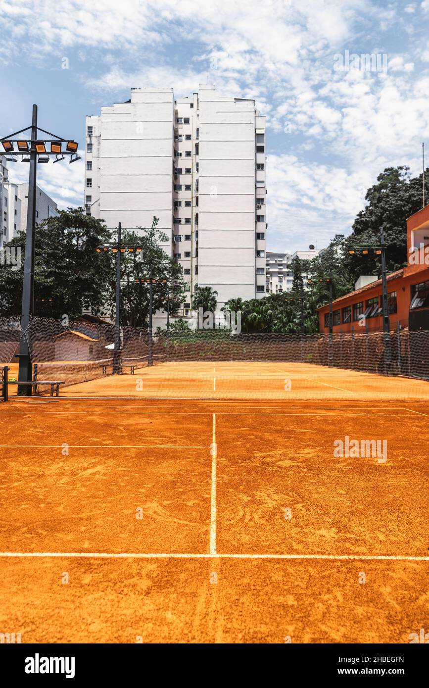 An outdoor view of a sports club with four tennis courts with clay