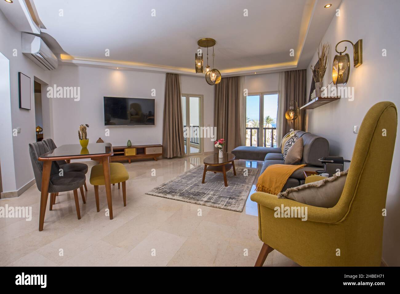Open plan living room lounge area in luxury apartment show home showing interior design decor furnishing with balcony terrace Stock Photo