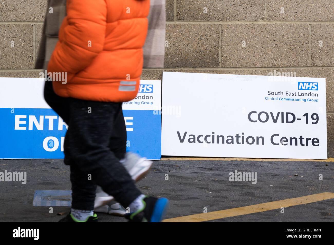 Greenwich London UK 19 December 2021. Southeast London clinical Commissioning group rolls out this weekend covid-19 vaccination for all eligible adults at The Valley, Charlton Athletic FC. Two young women dressed up on Stilts performing at the entrance to vaccine centre welcome people to get vaccinated to stop the surge of Omicron variant of coronavirus in the winter leading up to Christmas festive season. Credit: Xiu Bao/Alamy Live News Stock Photo