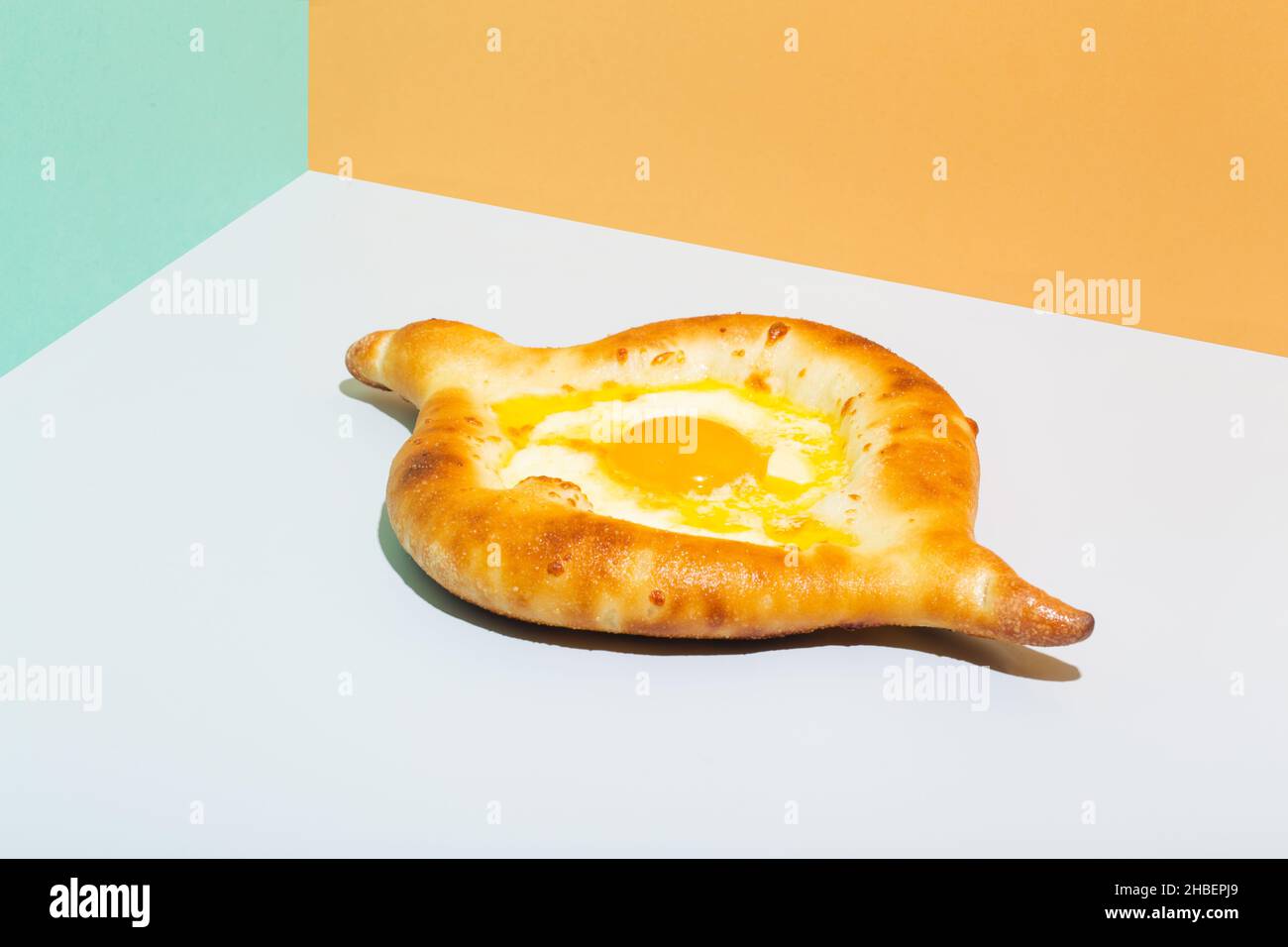 Closeup on caucasian flat bread adjarian khachapuri with egg on orange background Stock Photo