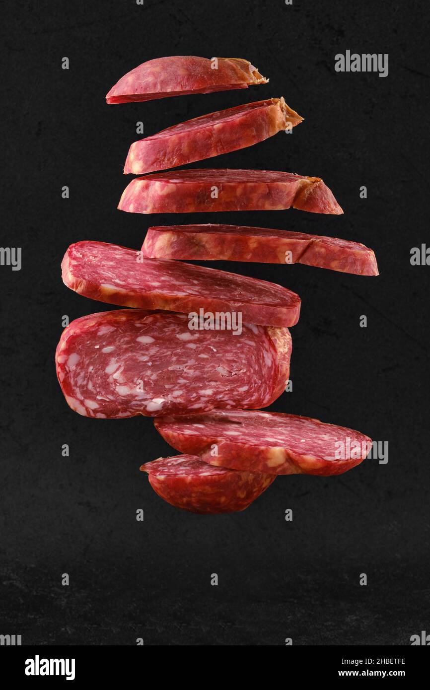Levitating slices of smoked beef sausage over black background Stock Photo