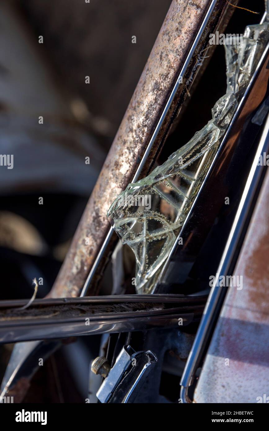 Pieces of safety glass remain in a shattered window frame of a rusty ...