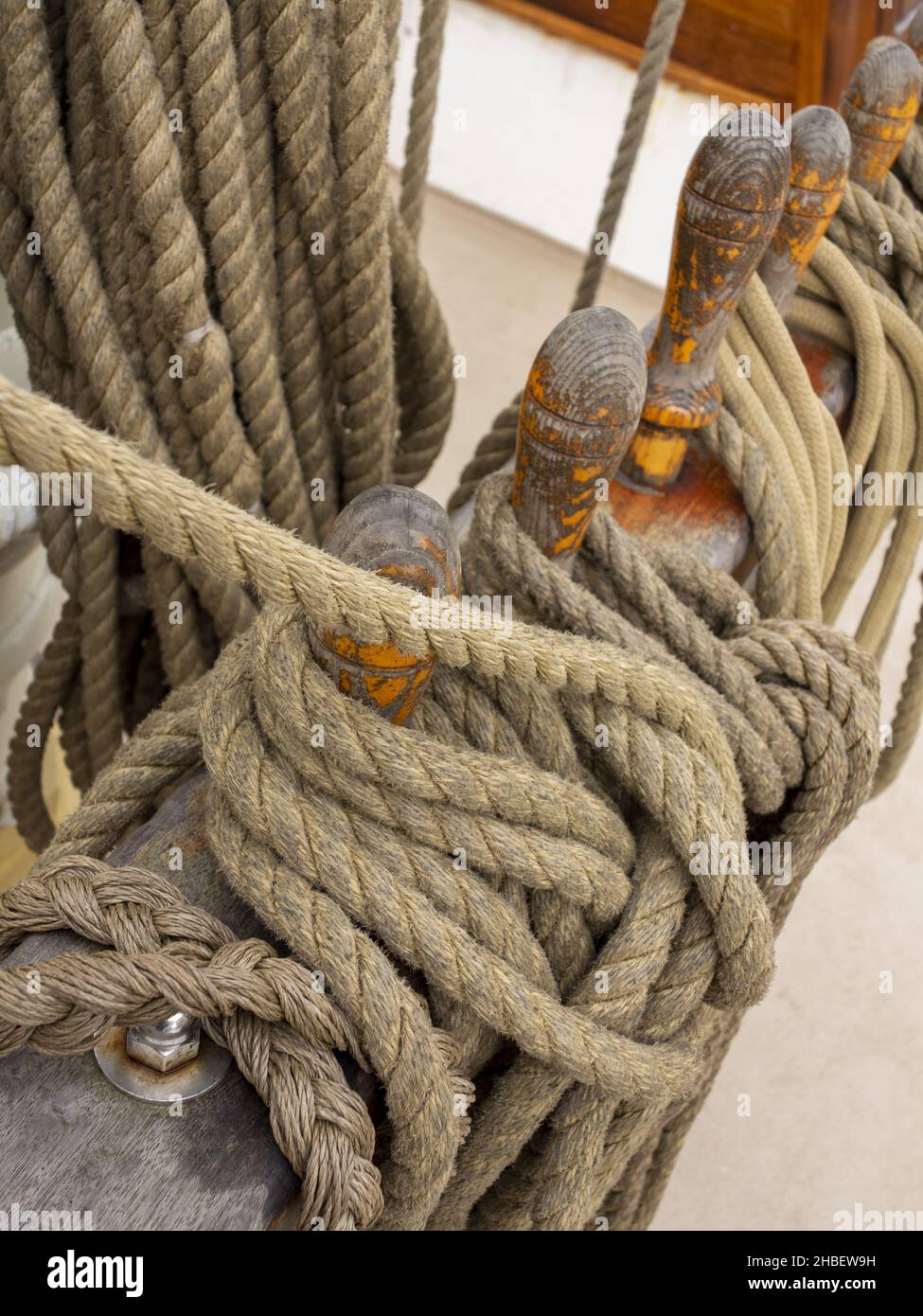 A vertical shot of thick ropes wrapped on a wooden pole Stock