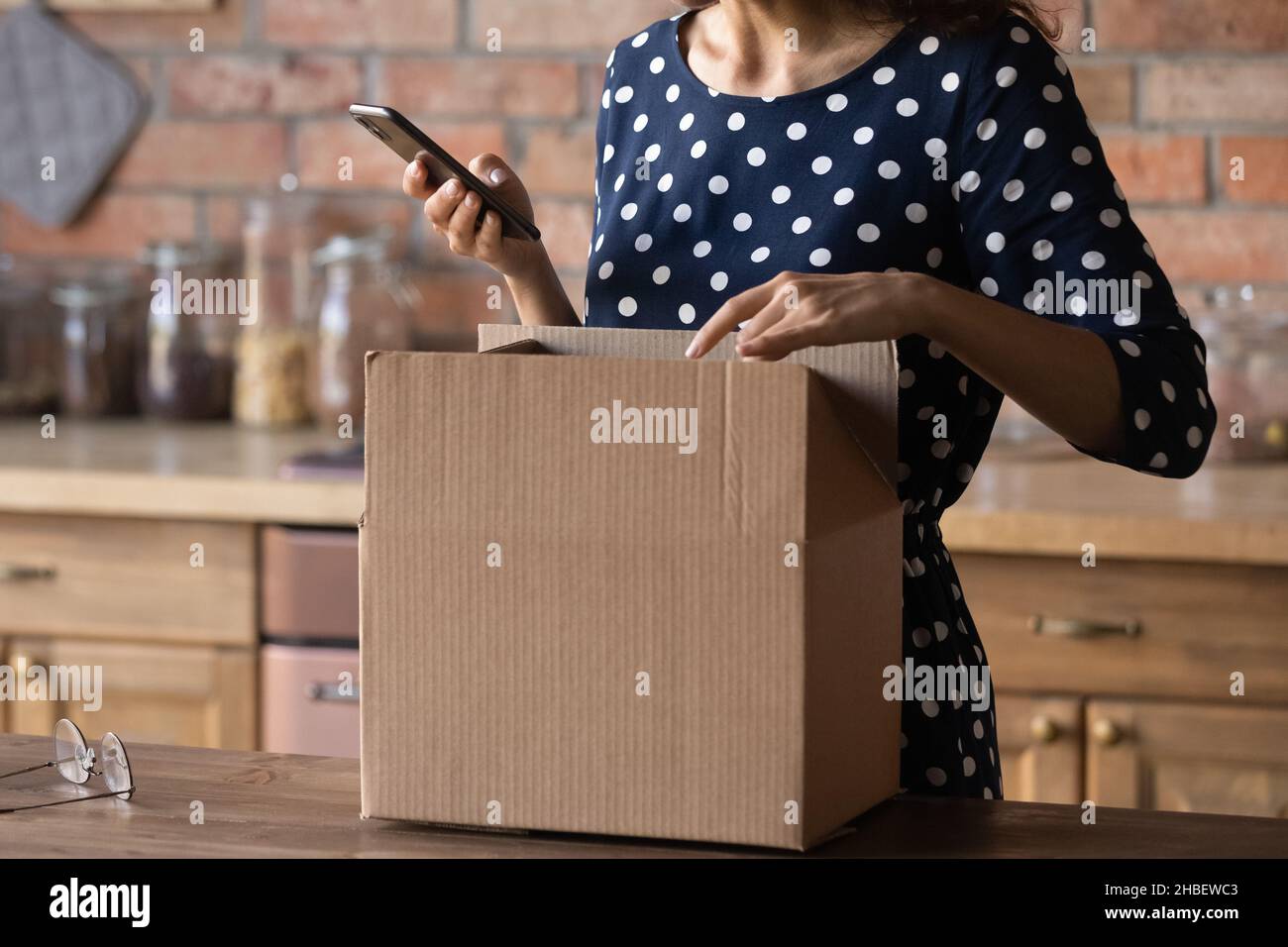 Close up cropped young female customer unpacking carton parcel. Stock Photo