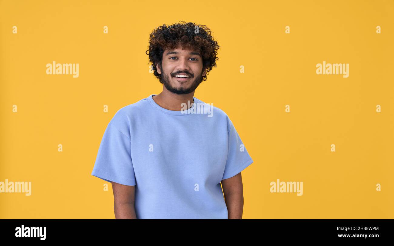 Smiling young indian guy standing isolated on yellow background. Stock Photo
