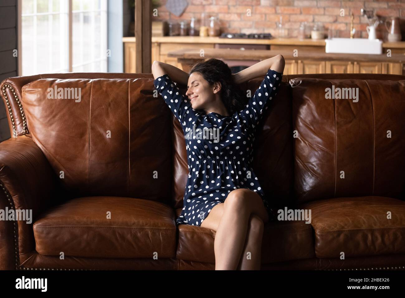 Beautiful latin woman daydreaming on comfortable couch. Stock Photo