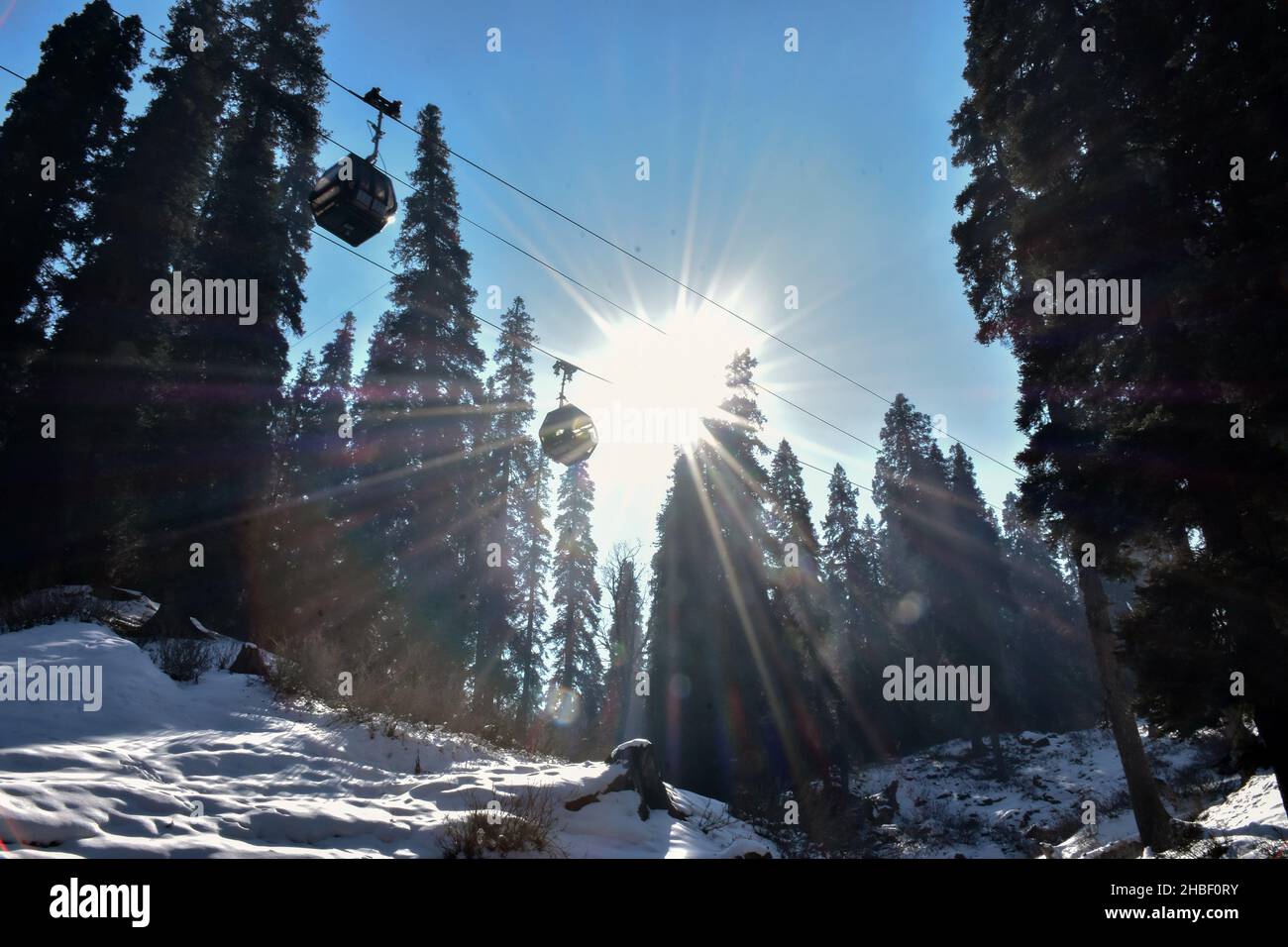 Cable cars move above snow capped peaks during a cold winter day at a ...