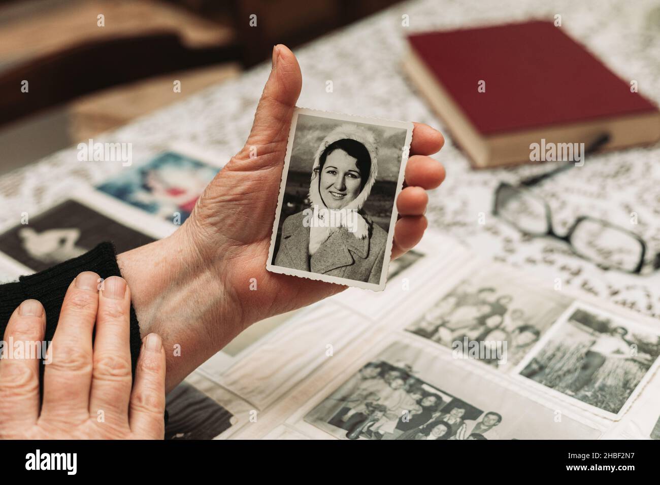 Elderly woman hands holding black and white photo of the young woman. Passing of time concept Stock Photo