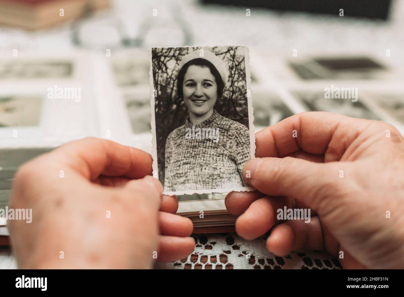 Elderly woman hands holding black and white photo of the young woman. Passing of time concept Stock Photo