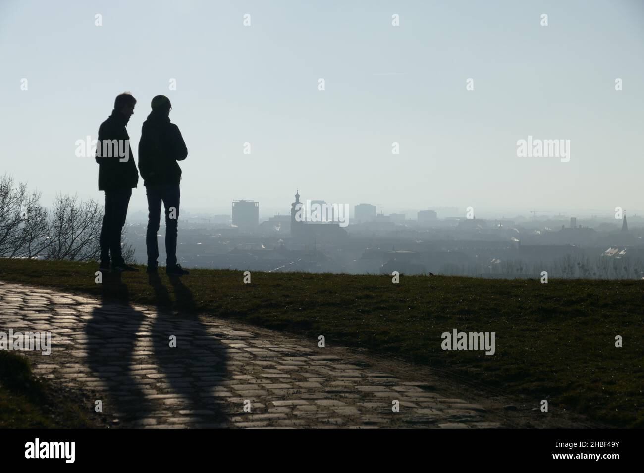 View over foggy town at an autumn day. in cold season. Two friends silhouette. Stock Photo