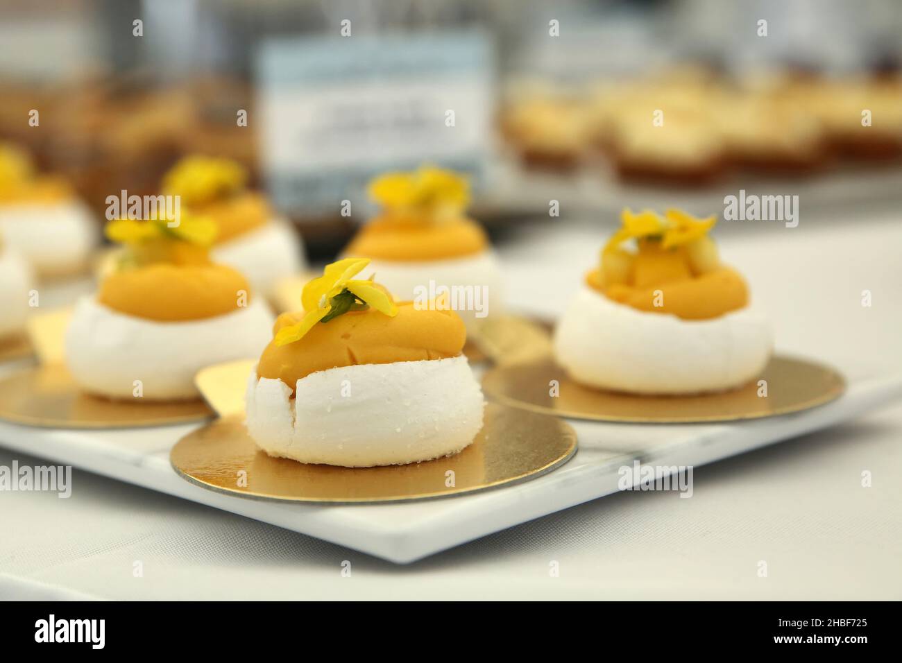 Beautiful elegant tray of lemon meringue canapes. Food ready for a garden party, Wedding or special event. Decorated with a petal. Stock Photo