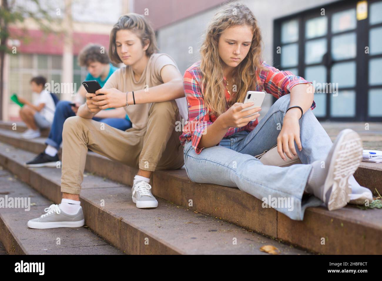 Group of teenagers smartphones sitting on stairs in school campus Stock ...