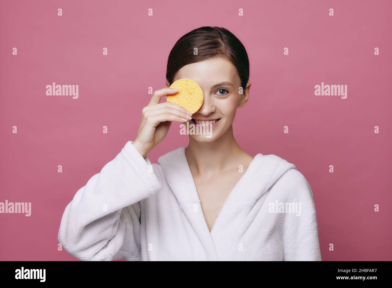 Young beautiful smiling girl holds cleansing sponge Stock Photo