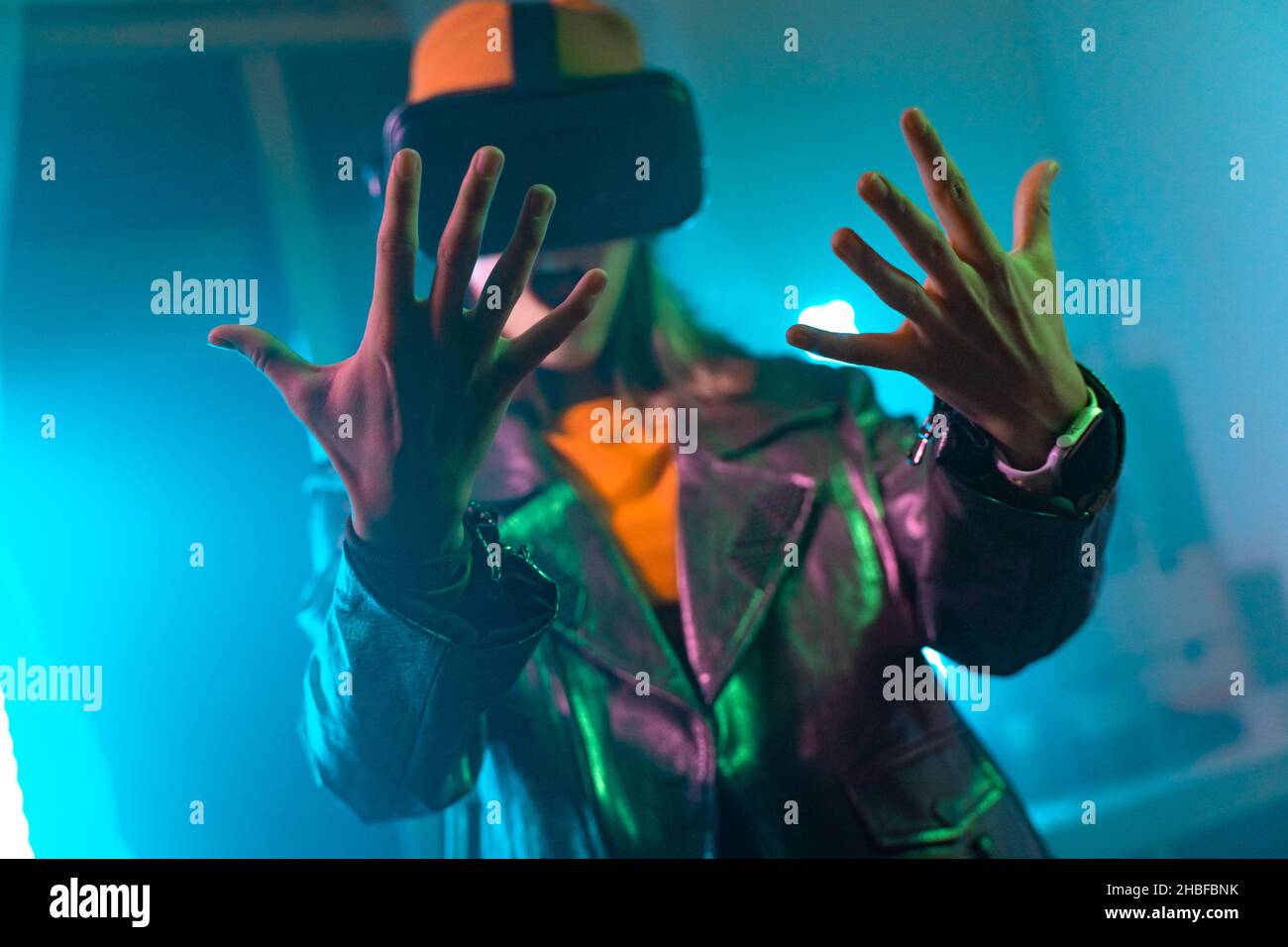 Wireless technologies. Young woman using virtual reality glasses in the dark room with neon lighting. Stock Photo