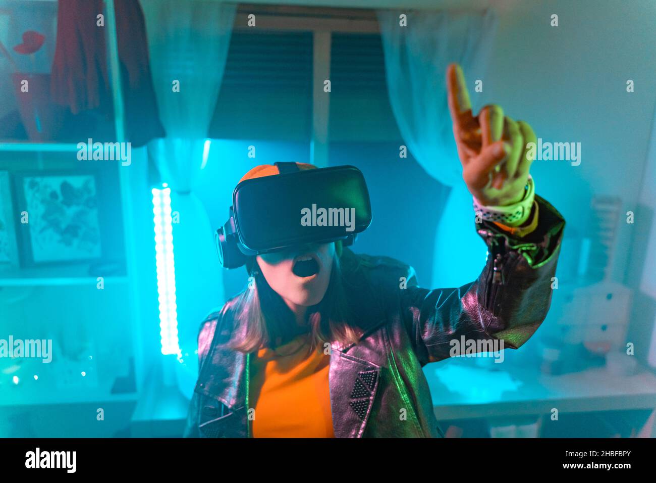 Wireless technologies. Young woman using virtual reality glasses in the dark room with neon lighting. Stock Photo