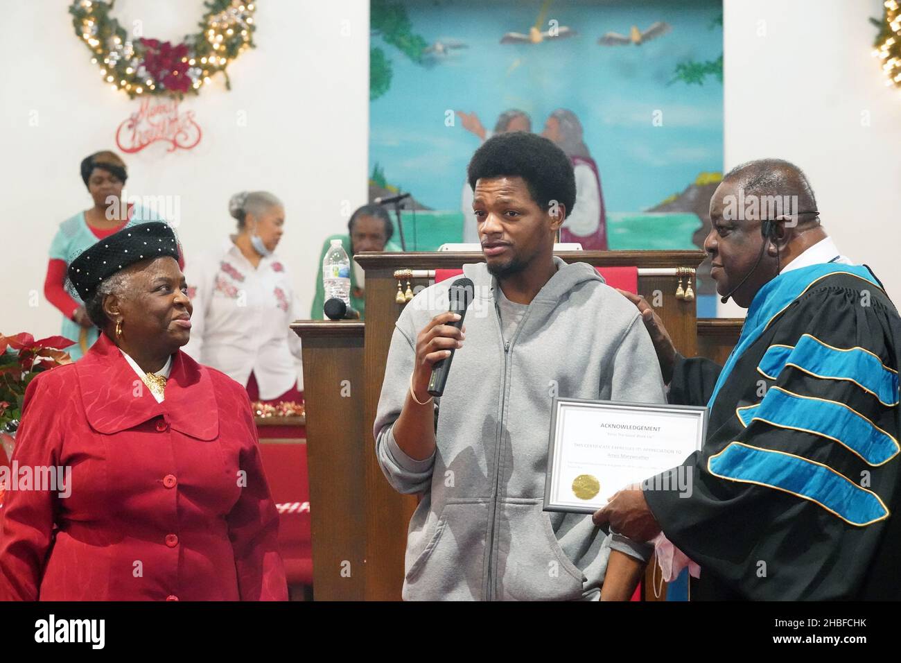 Arnez Merriweather (C) makes his remarks after being recognized by Dr. Maggie Williams and Pastor Donald Ray McNeal for his actions of saving a baby and mother from a fire, during a service at the Hopewell Missionary Baptist Church in St. Louis on Sunday, December 19, 2021. Merrriweather saved a 3-year-old girl whose mother tossed her out of a second-floor window to escape a fire at an apartment building in north St. Louis on Monday, November 29, 2021. Merriweather then caught the mother who jumped. Merriweather, 30, said he did it by remaining calm and simply doing what was needed. Credit: UP Stock Photo