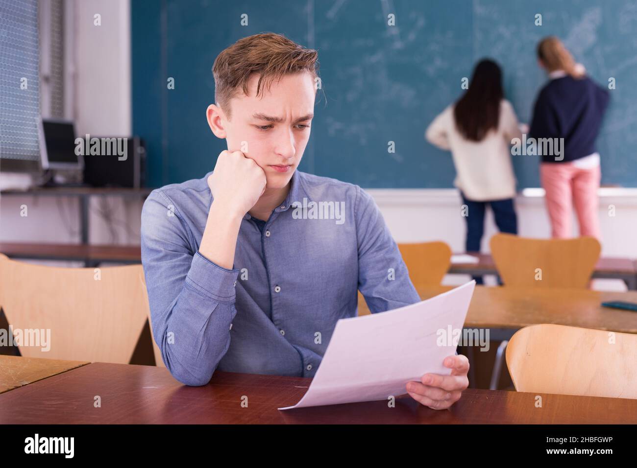 Young thoughtful guy preparing for the exam in classroom Stock Photo