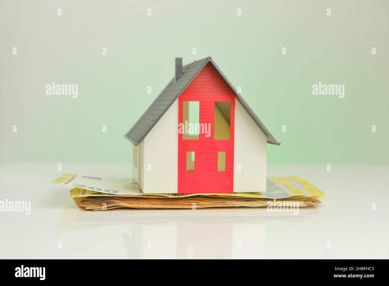Buying and building a house.House and money. Mock house with gray roof on euro banknotes background.  Stock Photo