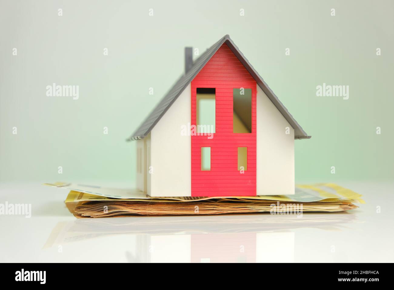 Buying and building a house.House and money. Mock house with roof on euro banknotes background. Stock Photo