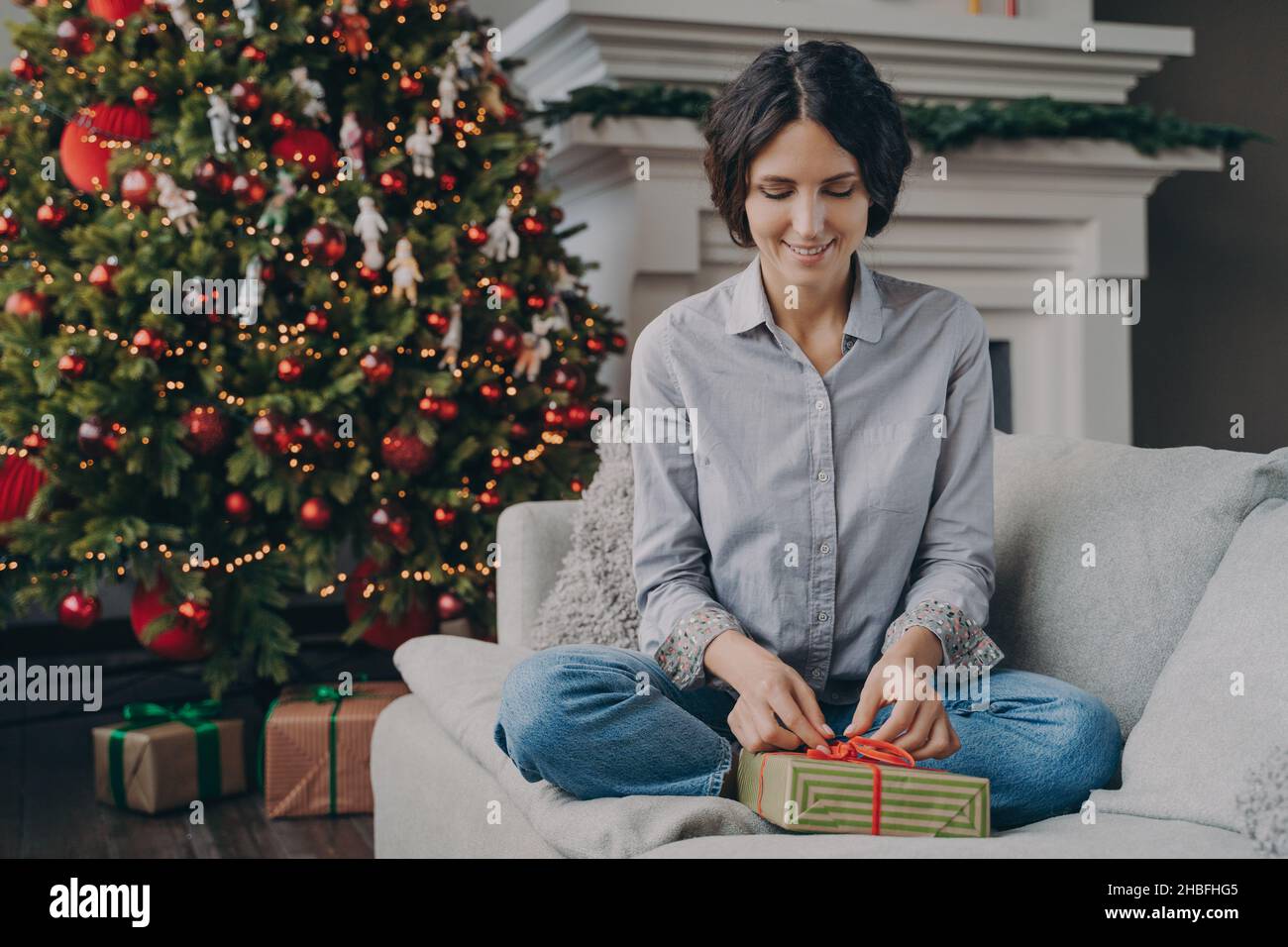 Happy Italian female preparing for Xmas at home, wrapping and packing christmas gift Stock Photo