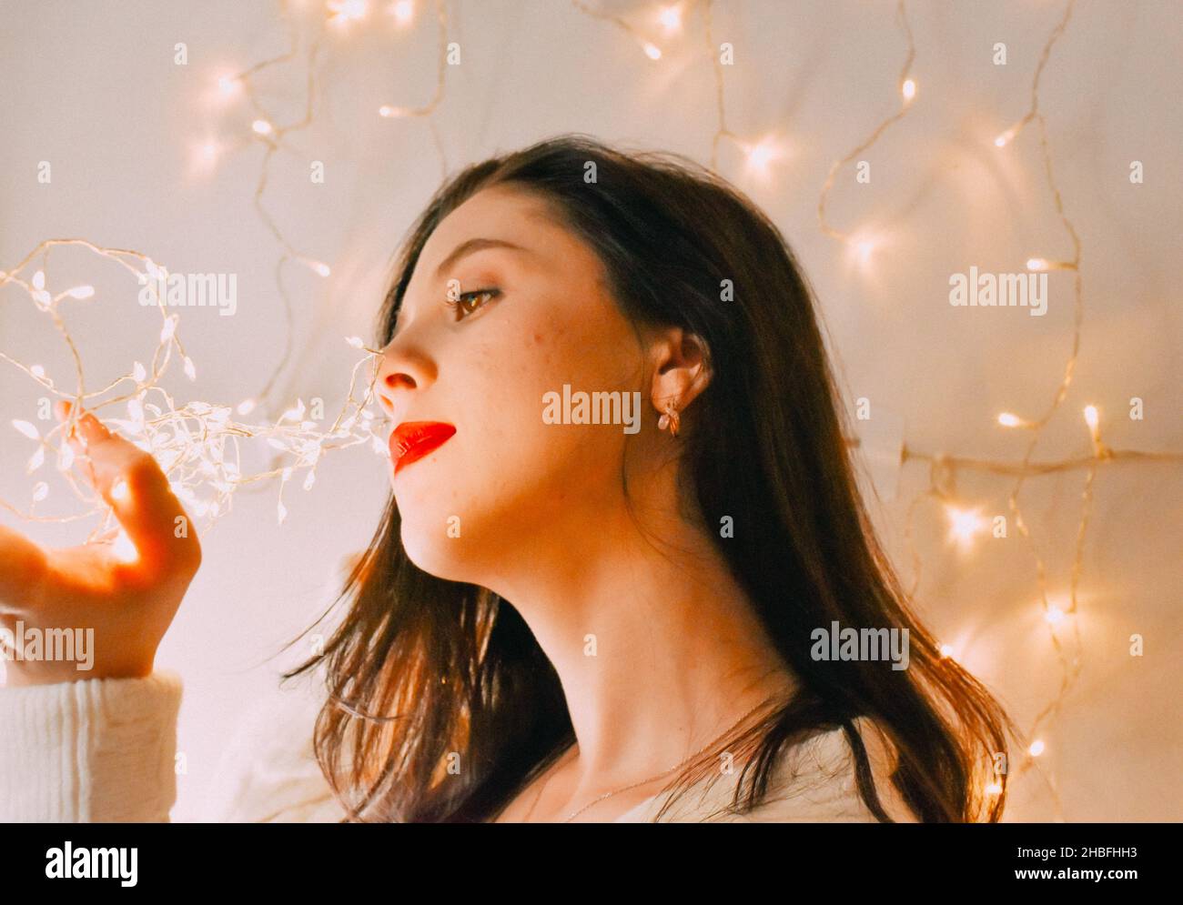 A closeup shot of a Caucasian girl with Christmas lights Stock Photo