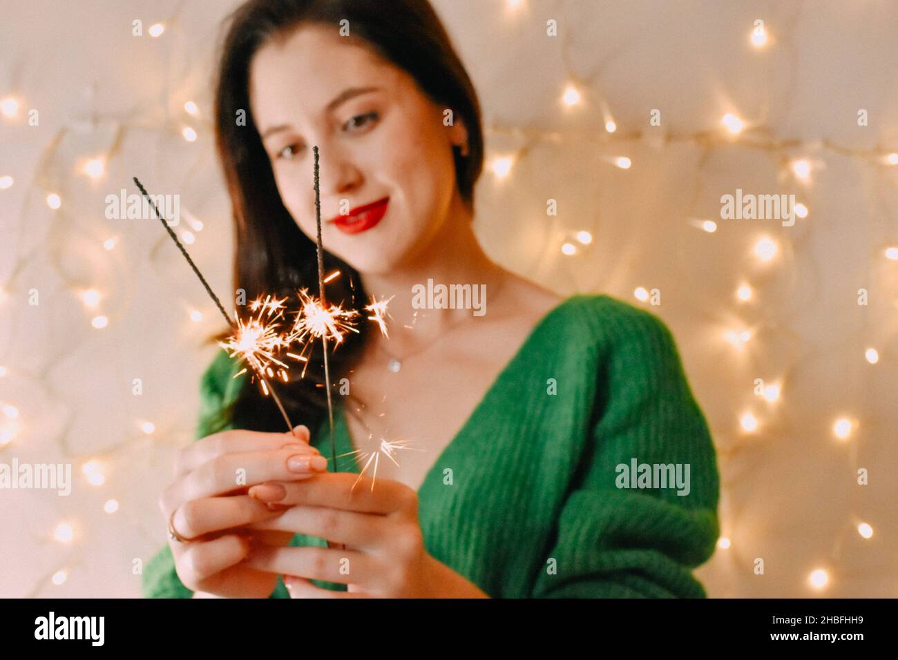 A closeup of a Caucasian girl with Christmas candles and Christmas lights on the wall Stock Photo