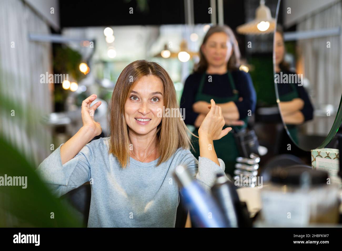 Delighted female client sitting in hairdressing chair after haircut