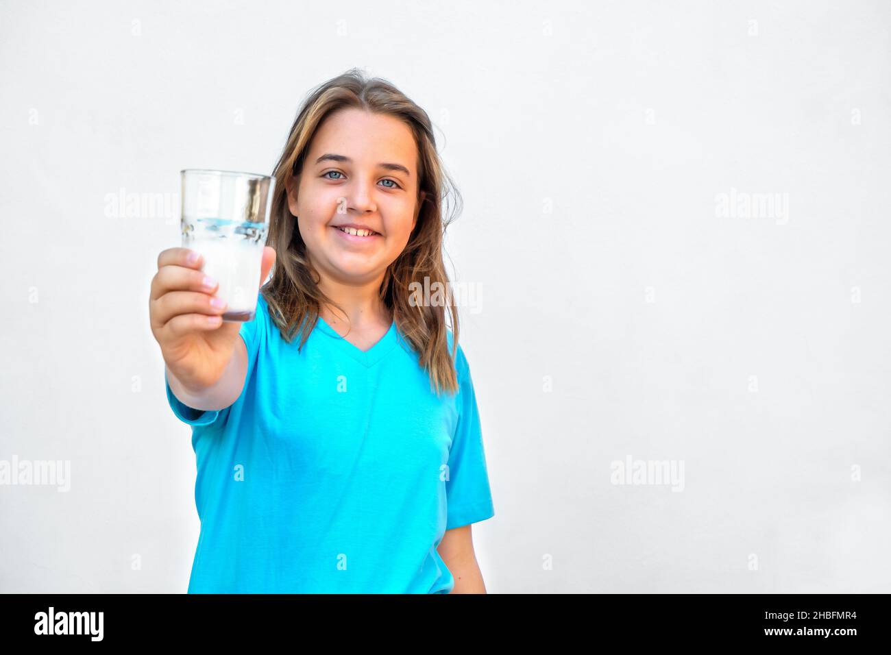 Teenage girl holds out a glass of milk with a smile Stock Photo