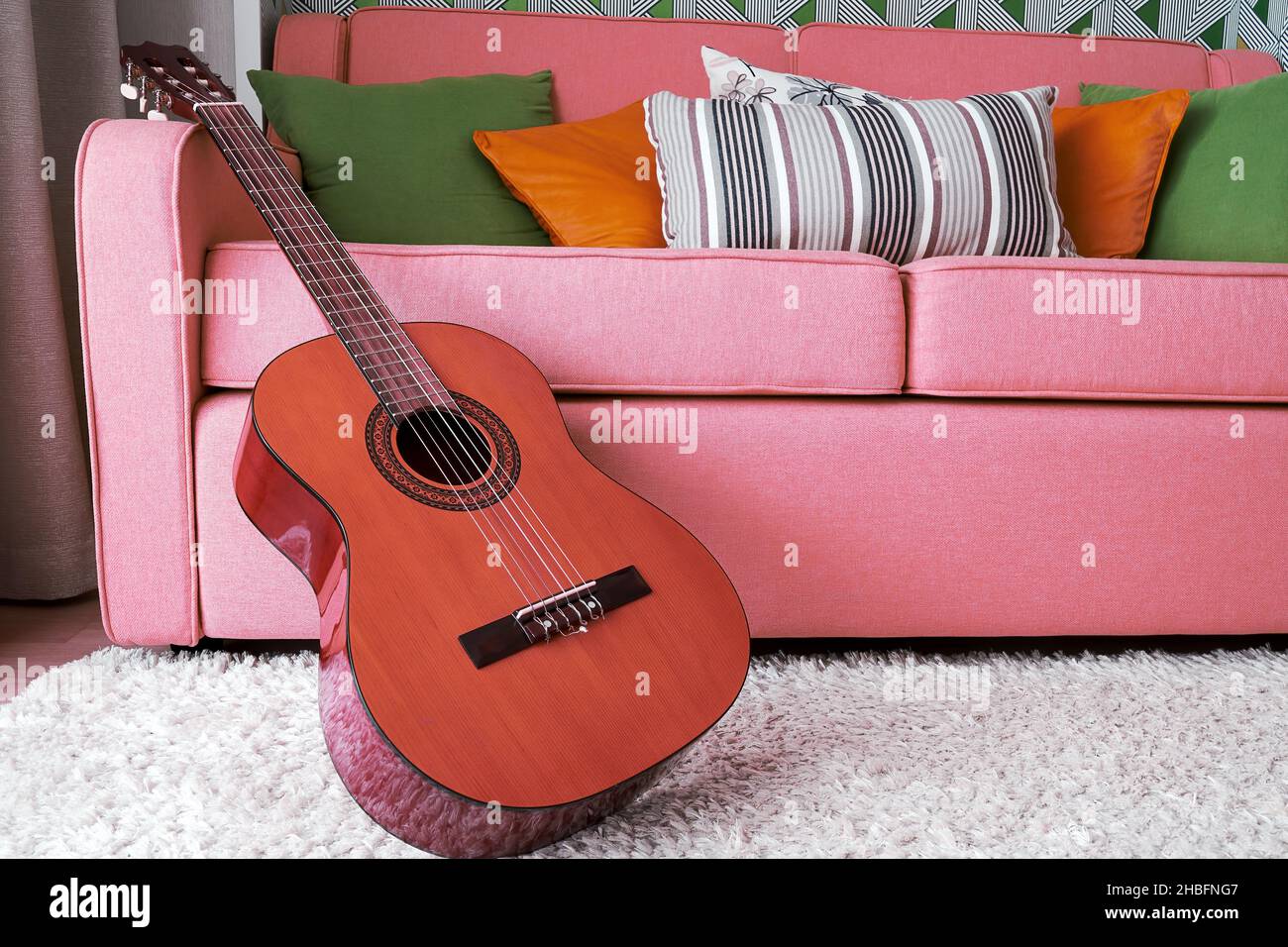 Classic acoustic guitar in the pink interior. Music hobby backgrounds Stock Photo