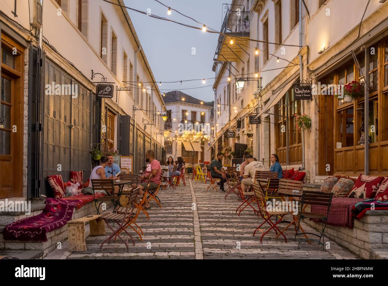 Unidentified people sits in cozy outdoor cafe in Gjirokastra old town Stock Photo