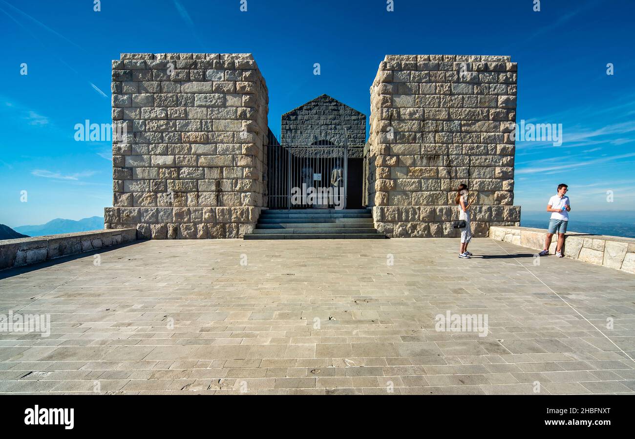 Lovcen National Park,Montenegro-September 14 2019:Under blue skies,two tourists wander the courtyard outside the famous tourist site and art installat Stock Photo